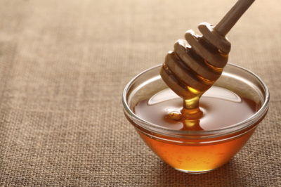 honey in a bowl slithering off of a honey dipper